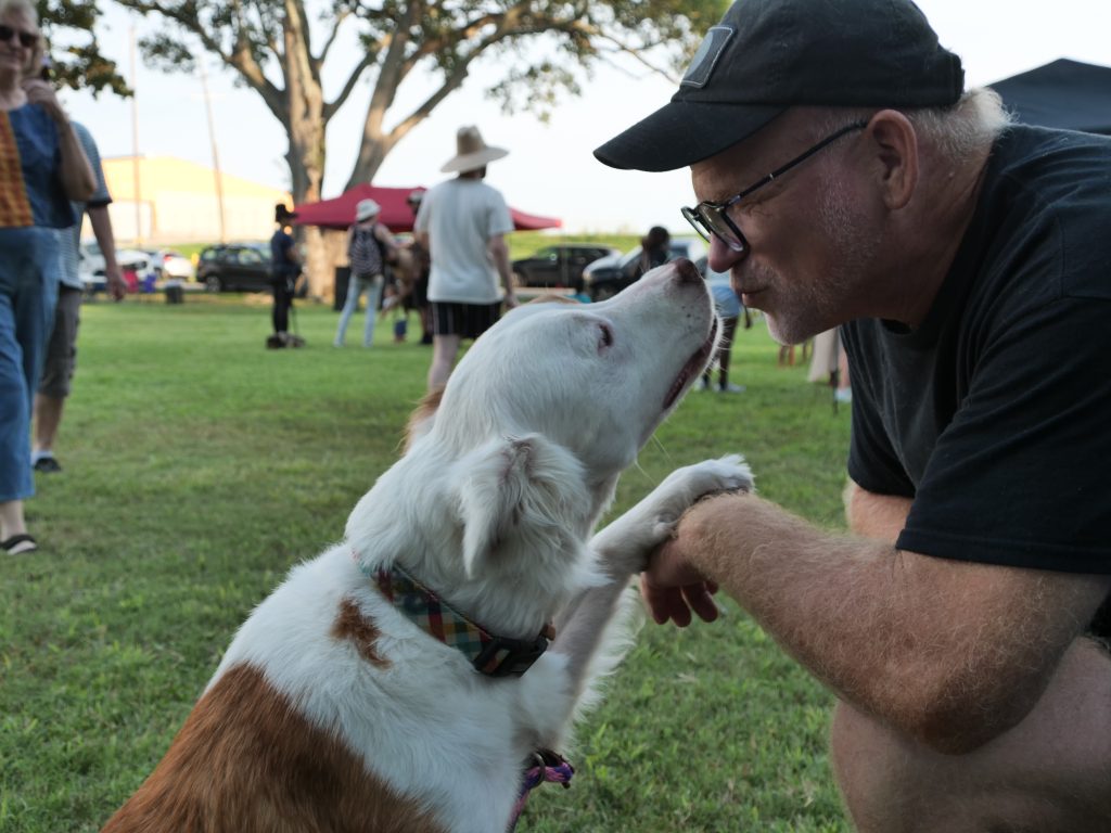Man gets close to his dog while on walk in park