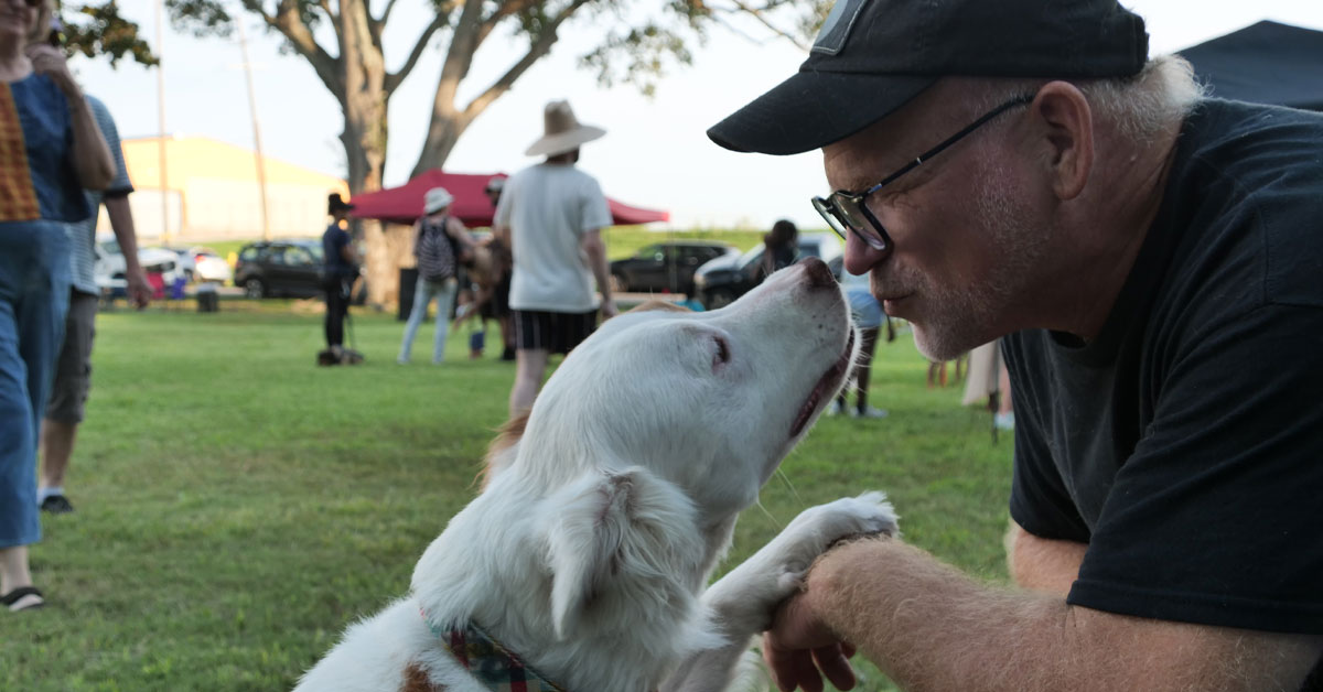 Man gets close to his dog while on walk in park