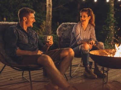 Image of two people seated at fire pit at night.